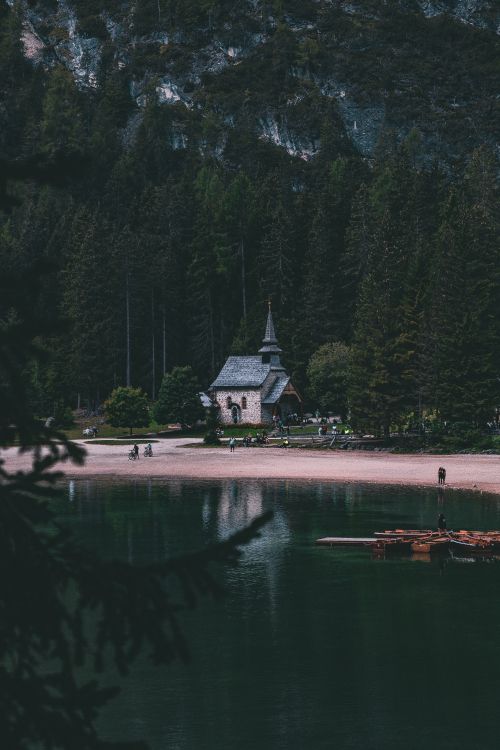 white and gray house near body of water and green trees during daytime