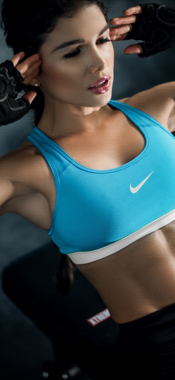 Image woman in blue sports bra and black pants holding black dslr camera