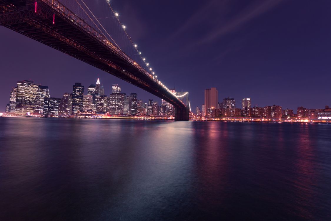 lighted bridge over body of water during night time