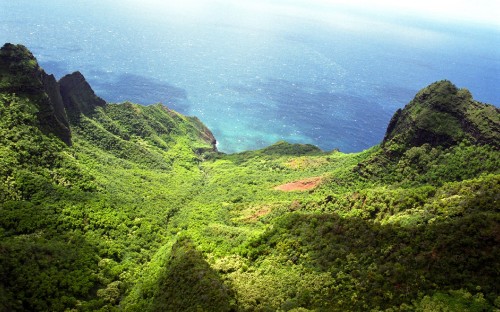 Image green mountain beside body of water during daytime