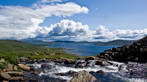 Image rocky shore under blue sky and white clouds during daytime