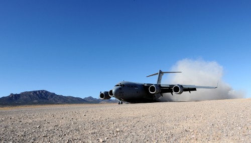 Image gray and black plane on brown sand under blue sky during daytime