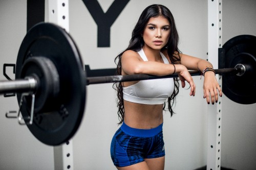 Image woman in blue denim shorts holding black dumbbell