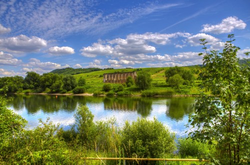 Image green grass field near lake under blue sky during daytime