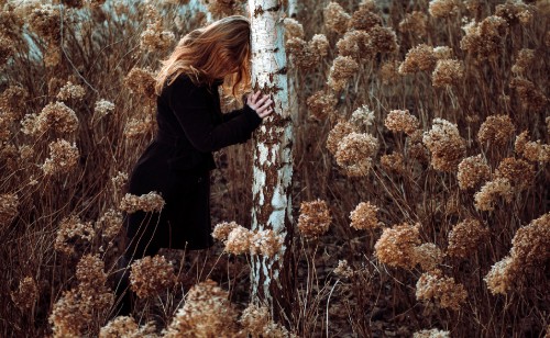 Image woman in black long sleeve shirt standing on brown grass field during daytime