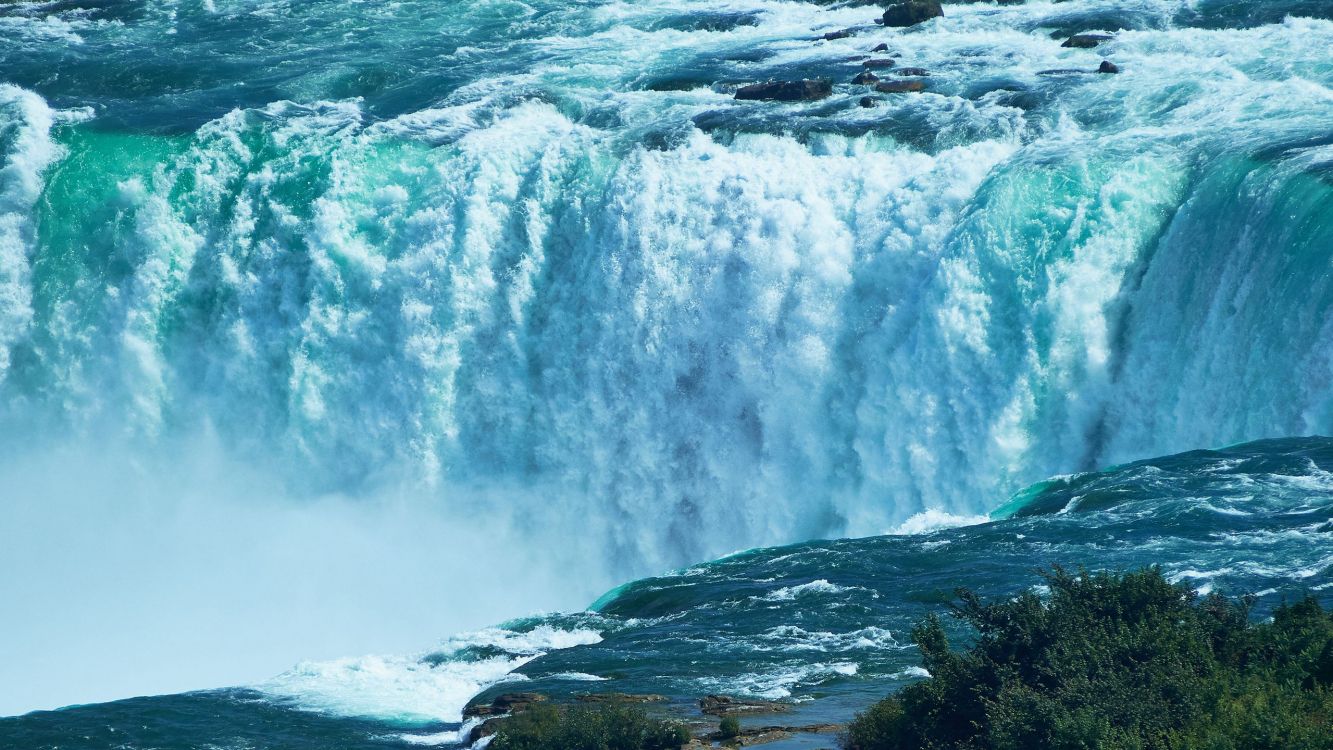 water falls on rocky shore during daytime