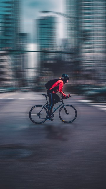 Image man in red jacket riding bicycle on road during daytime