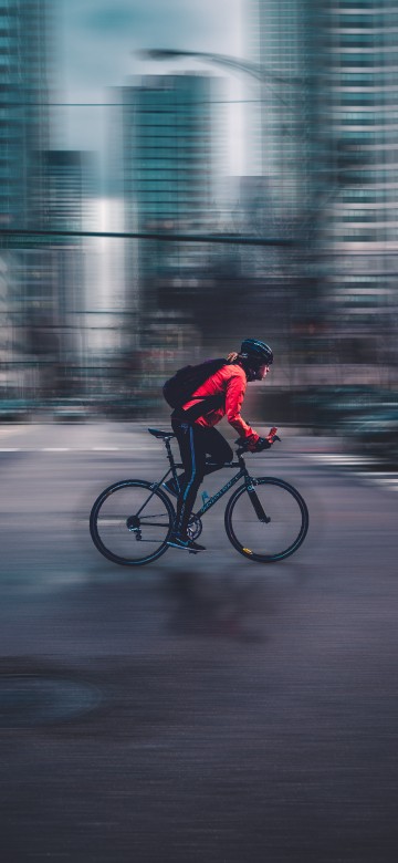 Image man in red jacket riding bicycle on road during daytime