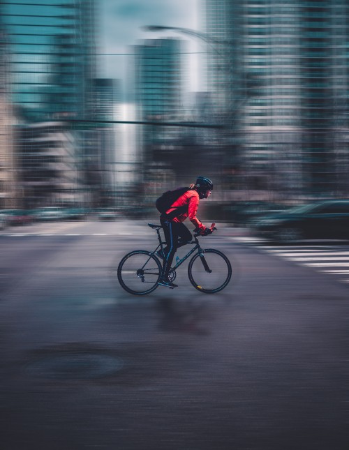 Image man in red jacket riding bicycle on road during daytime