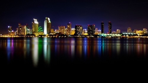 Image city skyline across body of water during night time