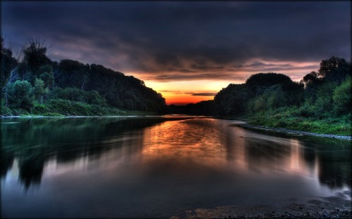 Image body of water near green trees during sunset