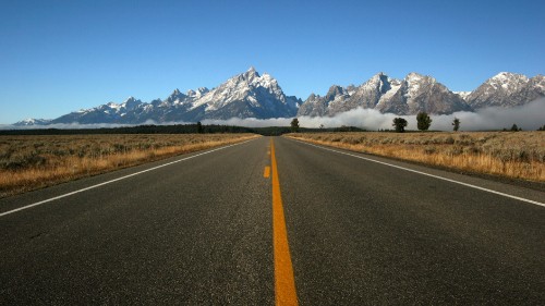 Image gray concrete road near mountain under blue sky during daytime