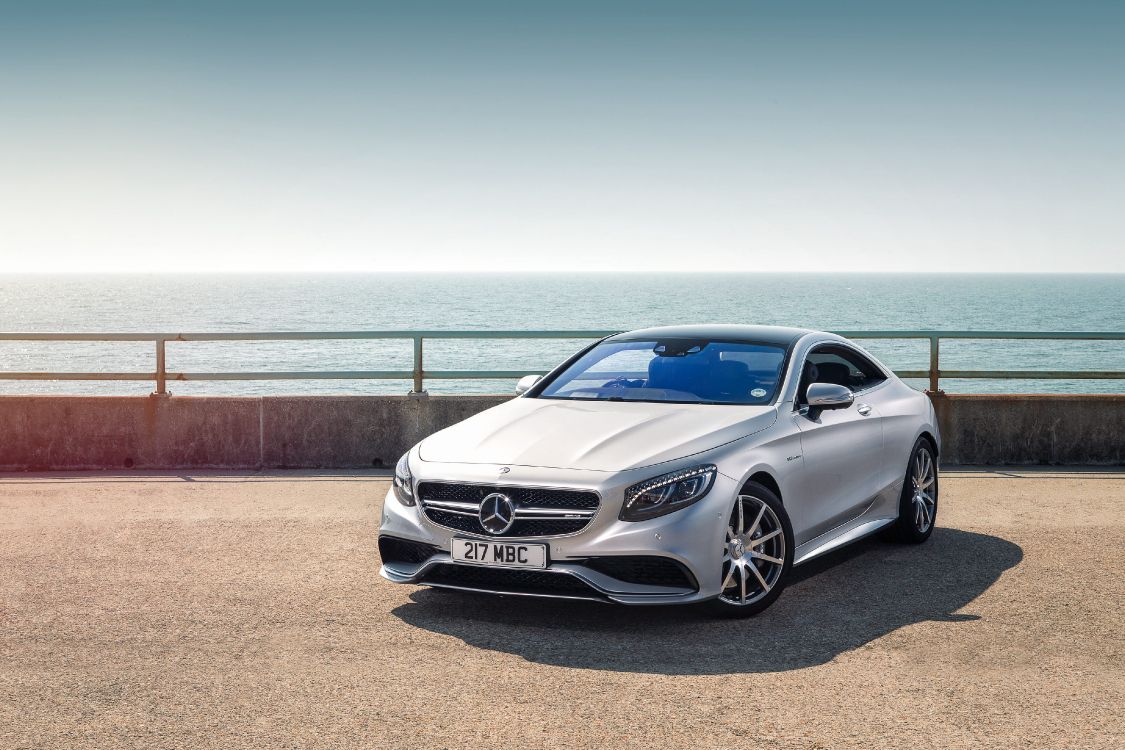 silver mercedes benz coupe parked on brown sand near sea during daytime