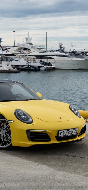 Image yellow ferrari 458 italia parked on gray concrete pavement near body of water during daytime