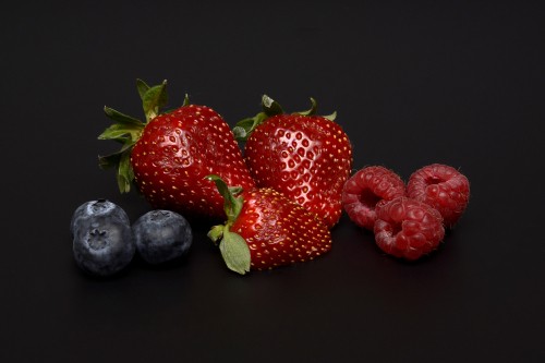 Image strawberries and black berries on white surface