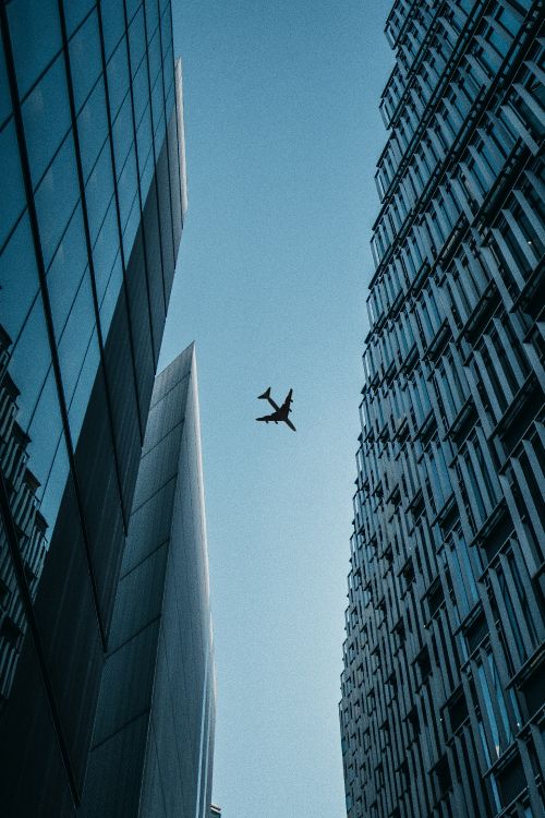 airplane flying over the building during daytime