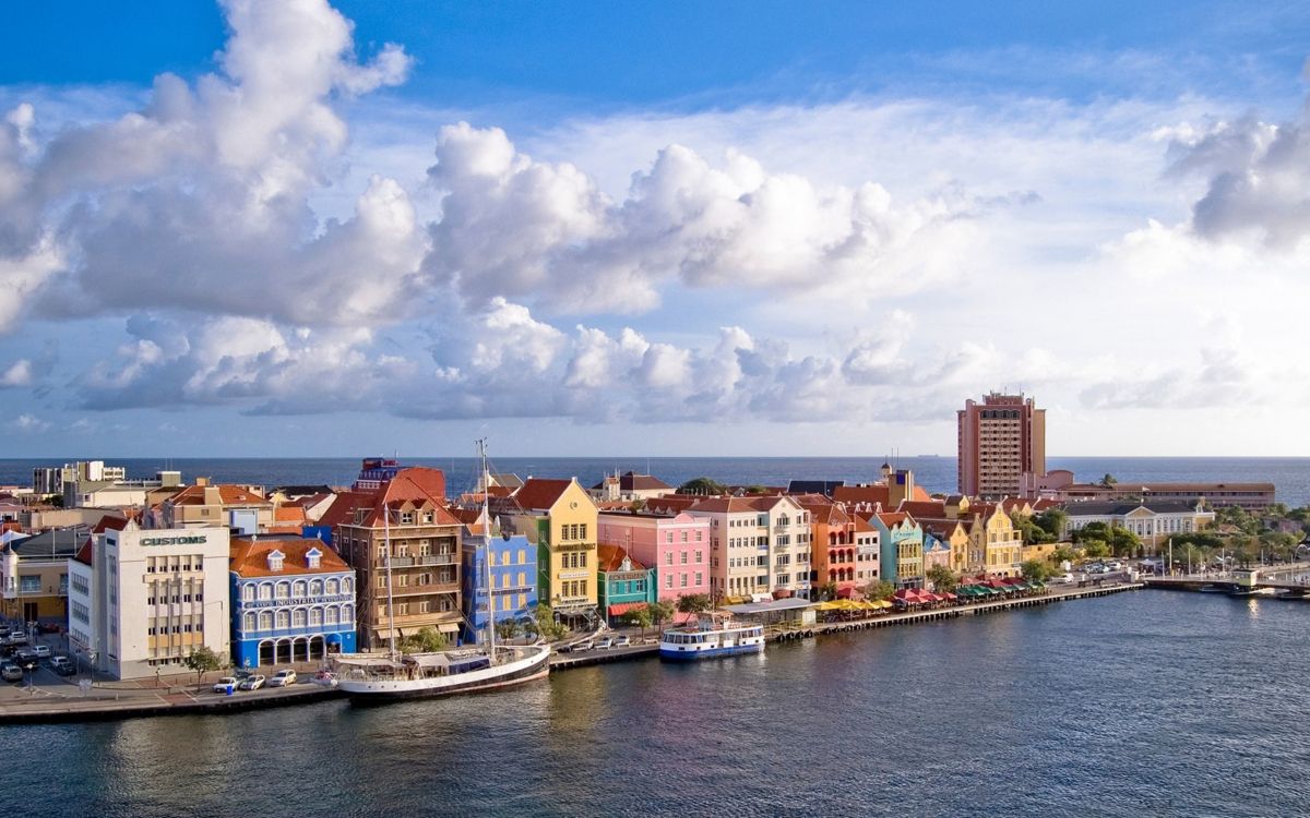 white and brown concrete buildings near body of water under blue and white cloudy sky during