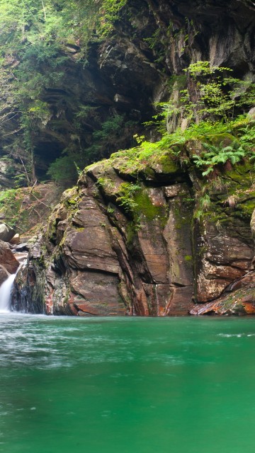 Image water falls between brown rocky mountain during daytime