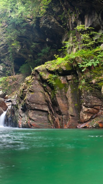 Image water falls between brown rocky mountain during daytime