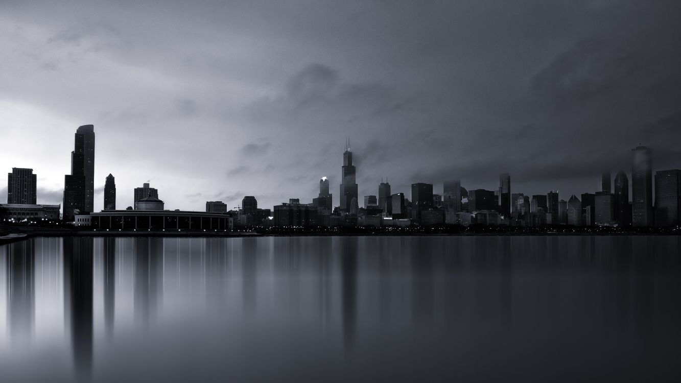 city skyline across body of water during night time