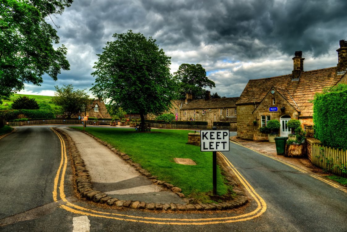 white and black road sign near green trees under cloudy sky during daytime