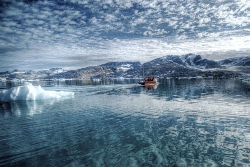 Image red boat on body of water near snow covered mountain during daytime