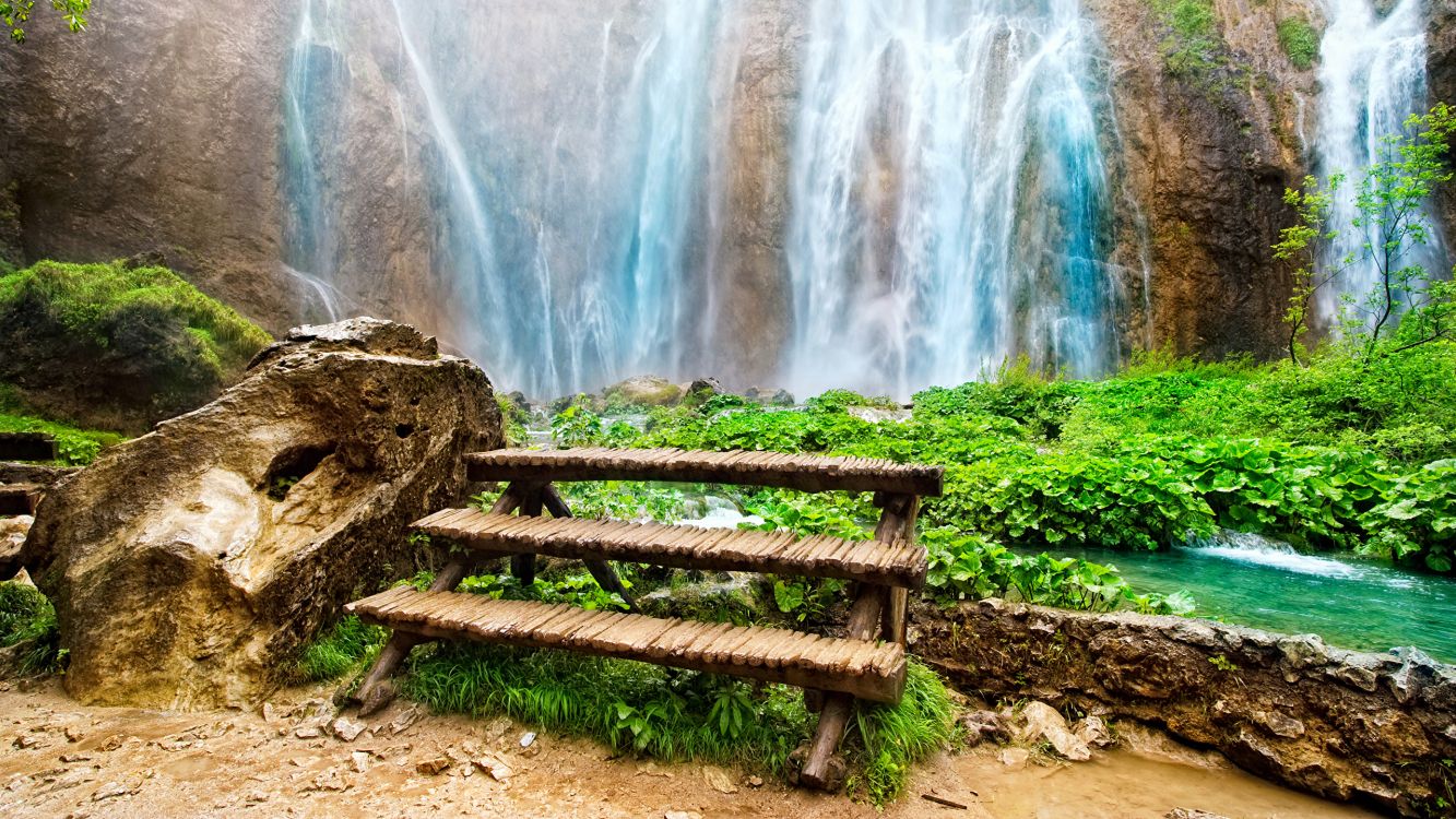 brown wooden bench near waterfalls during daytime