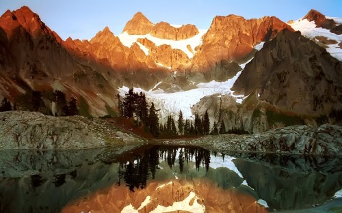 Image brown and white mountains near green trees and lake during daytime