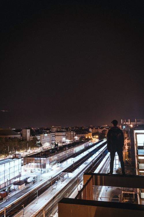 man in black jacket standing on brown wooden bridge during night time