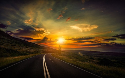 Image gray asphalt road between green grass field during sunset