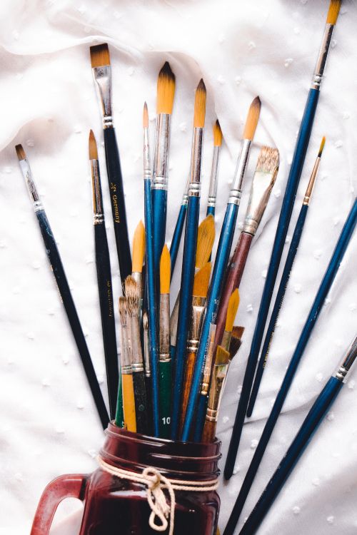 assorted color paint brushes on white textile