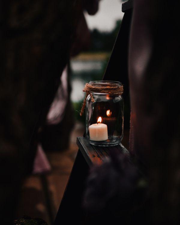 lighted candle in clear glass jar