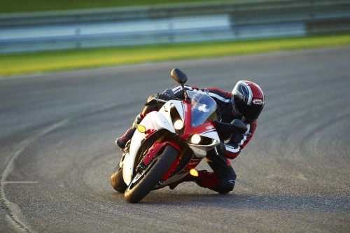 Image man in black and red motorcycle suit riding on sports bike