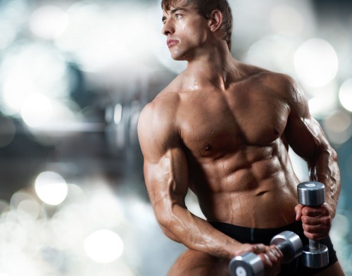 Image topless man in black shorts holding black dumbbell