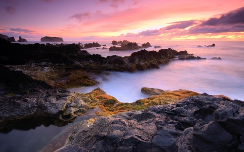 Image rocky shore with ocean waves under cloudy sky during daytime