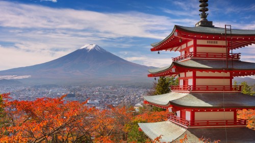 Image red and white concrete building near mountain under white clouds and blue sky during daytime