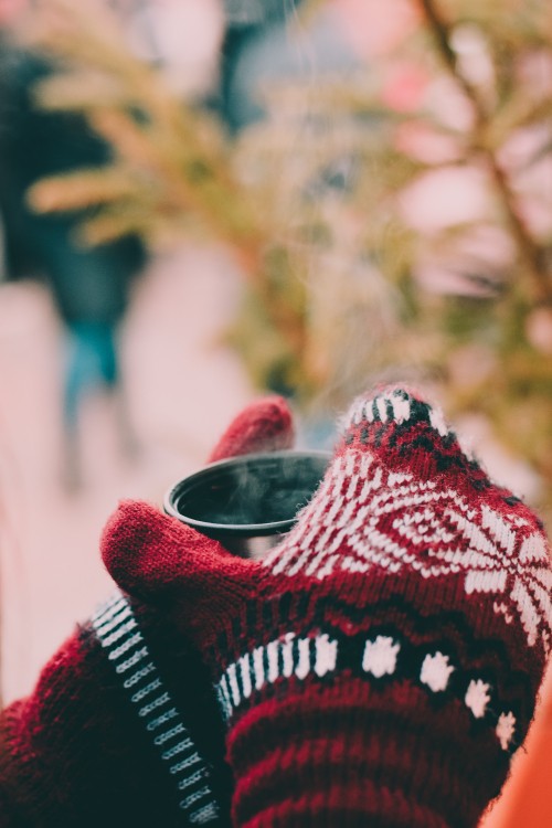 Image person in red white and black knit sweater holding black framed eyeglasses