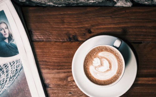 Image white ceramic cup with cappuccino on brown wooden table