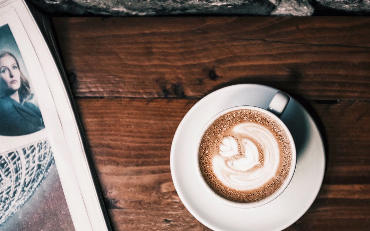 white ceramic cup with cappuccino on brown wooden table