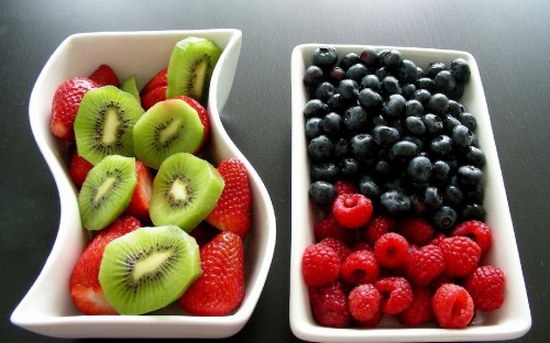 Image sliced kiwi and strawberries in white ceramic bowl