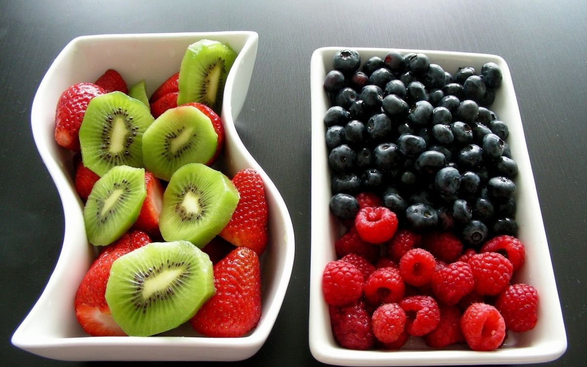 sliced kiwi and strawberries in white ceramic bowl