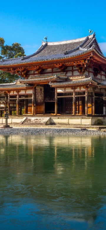 Image brown and white temple near body of water during daytime