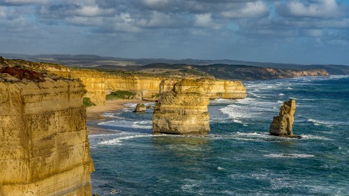 Image brown rock formation on sea under white clouds during daytime