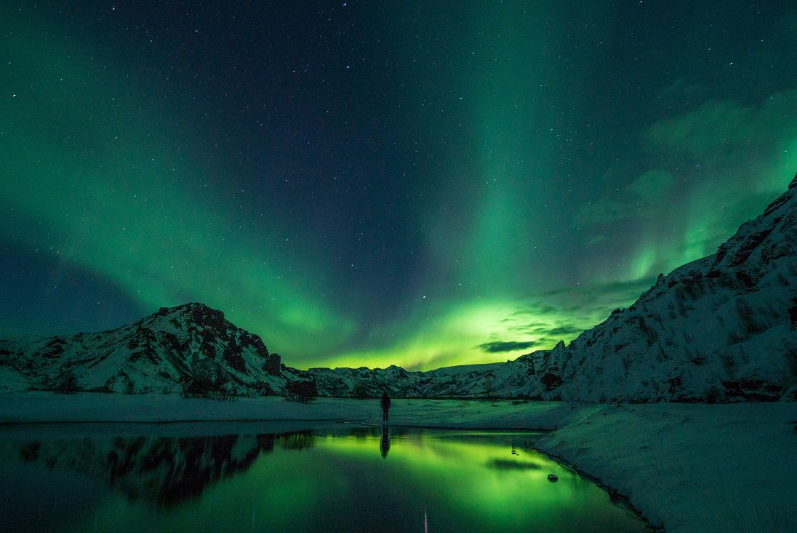 body of water near mountain during night time