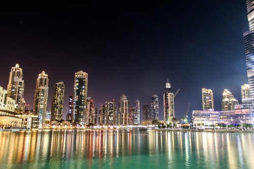 Image city skyline across body of water during night time