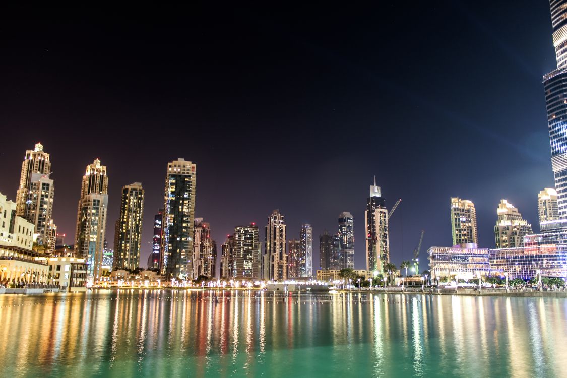 city skyline across body of water during night time