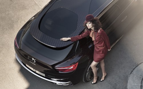 Image woman in red coat standing beside black car