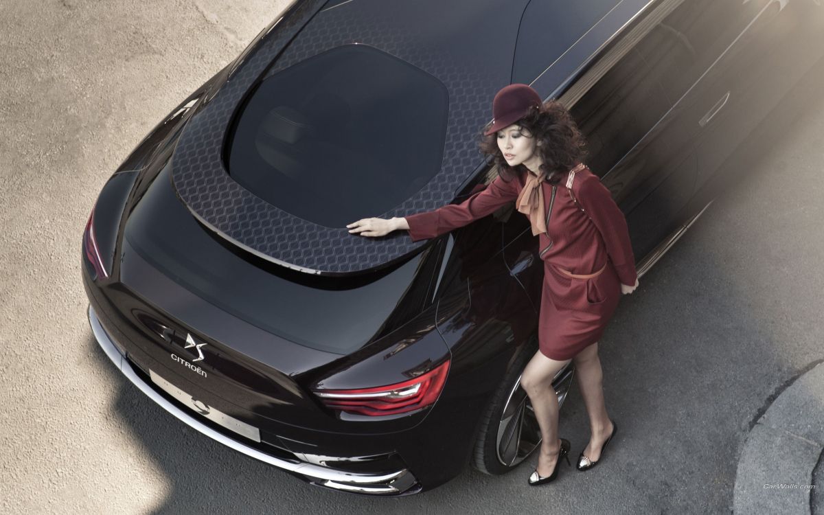 woman in red coat standing beside black car