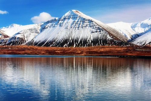 Image snow covered mountain near body of water during daytime