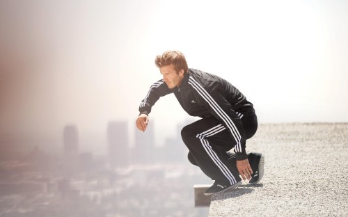 Image man in black leather jacket and black pants sitting on white concrete bench during daytime